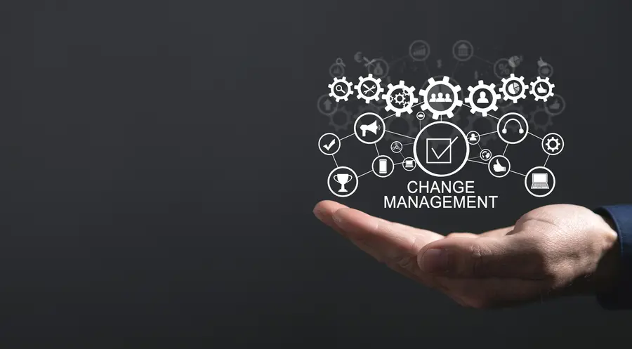 Zarządzanie zmianą technologiczną – grafika: dłoń, a nad nią zębatki i napis "change management"