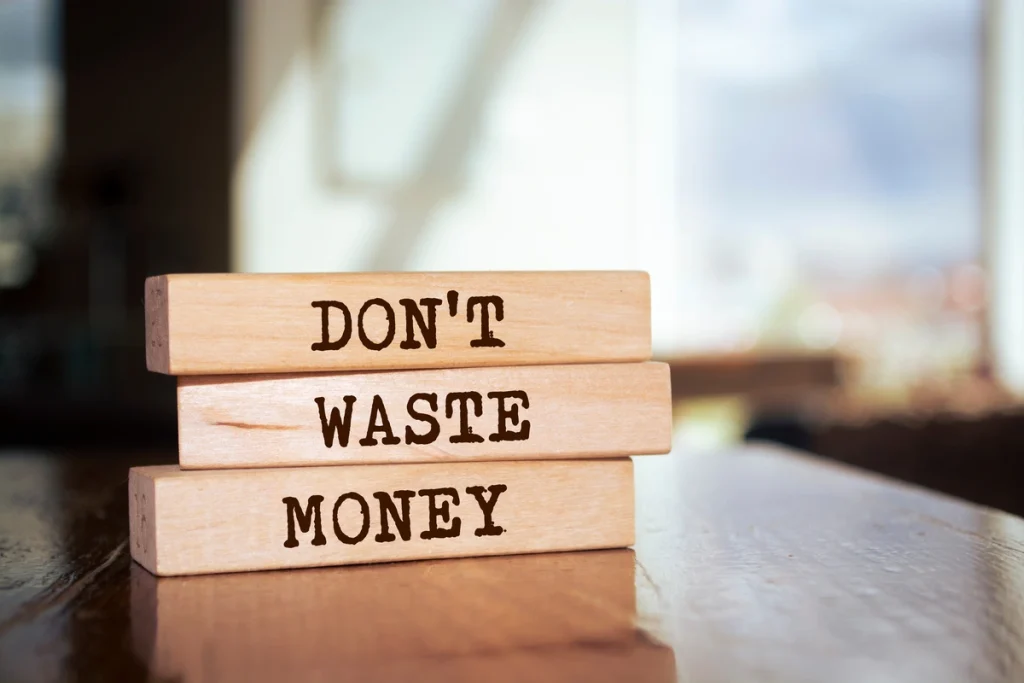 eliminacja marnotrawstw (trzy drewniane bloczki jeden na drugim z napisem: Don't waste money)