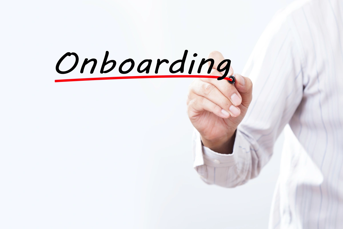 onboarding pracowników, offboarding w firmie (napis "onboarding" na białym tle, widoczna dłoń, która podkreśliła ten napis na czerwono
